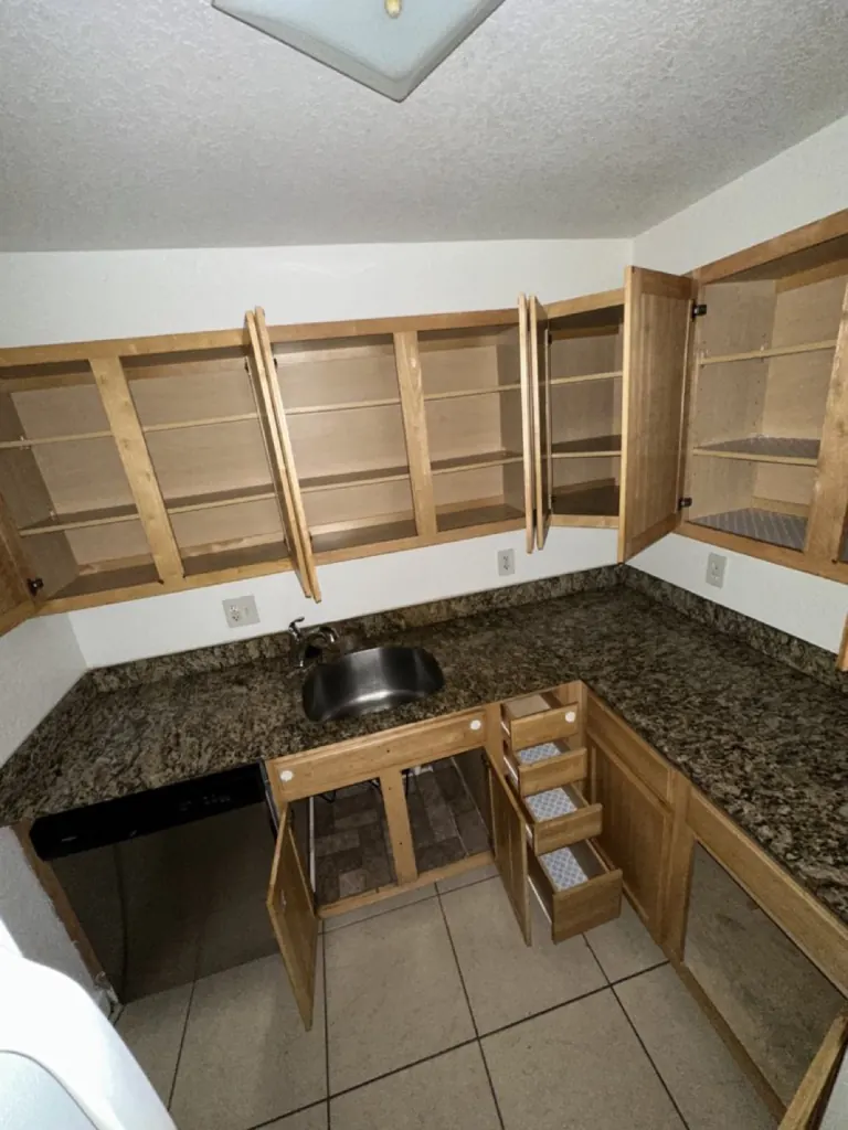 Empty Coral Springs condo kitchen with every cabinet open after a Casabela move-out clean